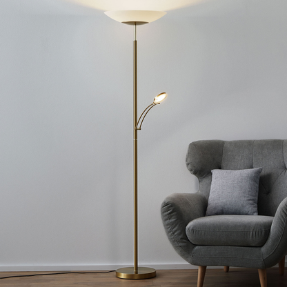 Alfred vloerlamp - messing uplighter met leesarm naast een fauteuil